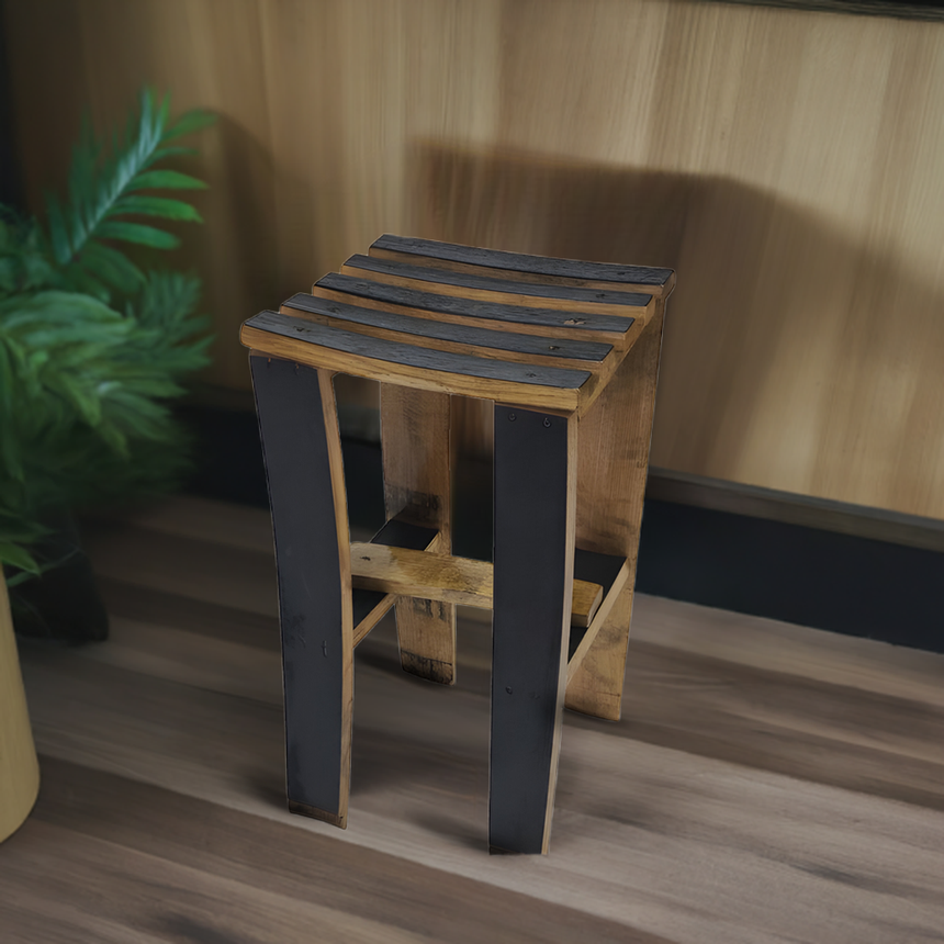 A Bar Stool Wooden, hand made from solid wood barrel staves with 24" to 30" height options, stands on a wood floor next to a green plant, bringing rustic charm to the space.