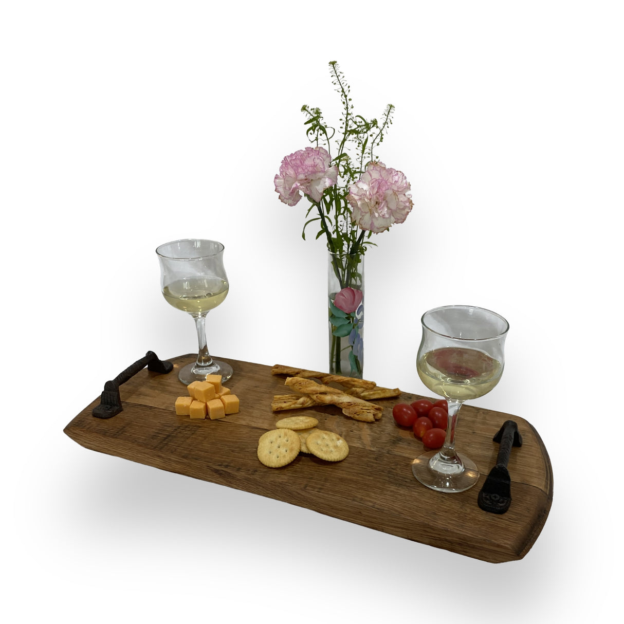 Two glasses of white wine, cheese, crackers, and tomatoes arranged on the Charcuterie and Cheese Rectangle Wooden Serving Board add rustic charm, with flowers in a vase behind.