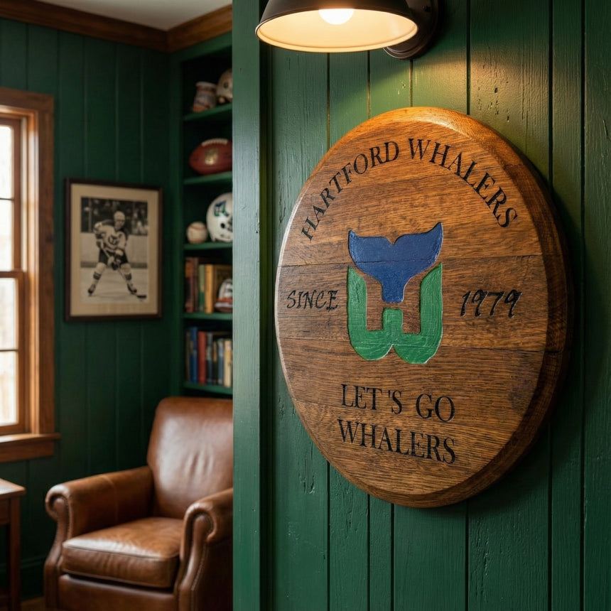 Small Barrel Head Art, handcrafted from reclaimed bourbon barrel heads and featuring the Hartford Whalers logo, displayed on a green wall in a cozy sports-themed room—a unique keepsake for any hockey fan.