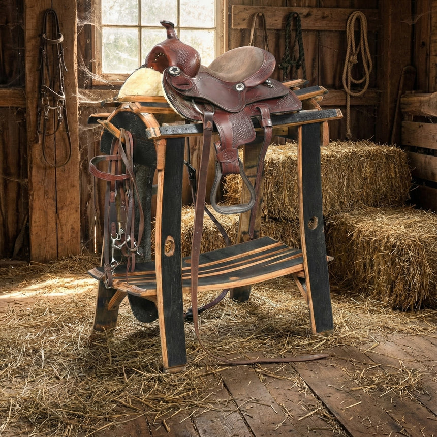A Saddle Stand holds a leather saddle in a barn surrounded by hay bales and wooden walls, creating an ideal equestrian tack storage display.