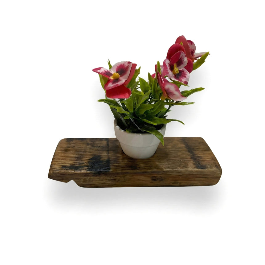 A Single Bud Vase made from a whiskey barrel stave, featuring red flowers and green leaves, sits on a rustic wooden shelf—perfect for adding farmhouse charm to your home decor.