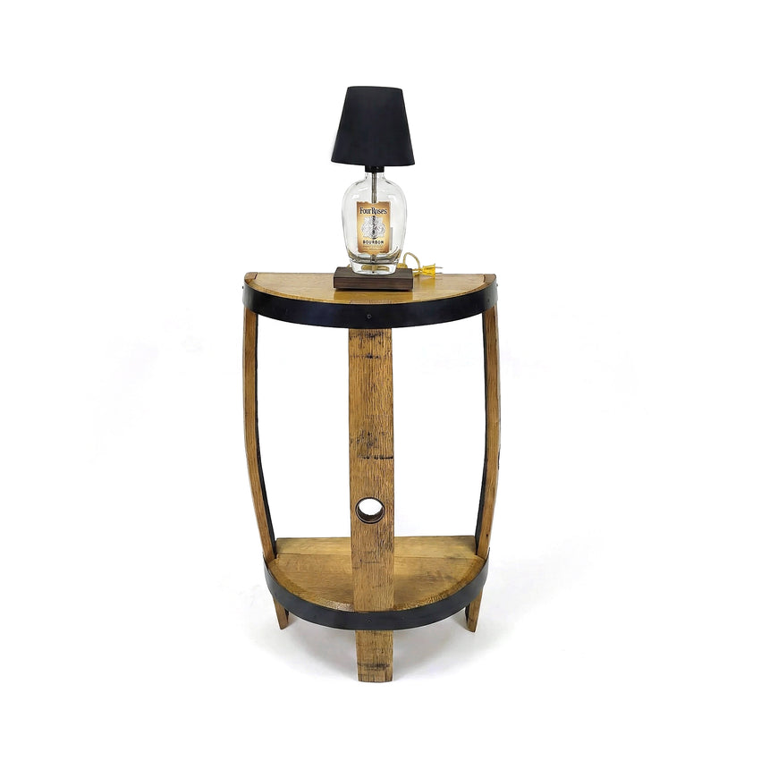 The Lamp Side Table is crafted from reclaimed whiskey barrel furniture, featuring a black-edged shelf and topped with a lamp with a sleek black shade for a rustic, stylish look.