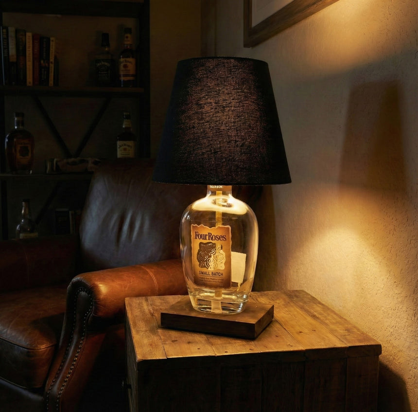 The Four Roses Lamp, crafted from repurposed Four Roses bottles, brings rustic elegance to a wooden table next to a leather chair.