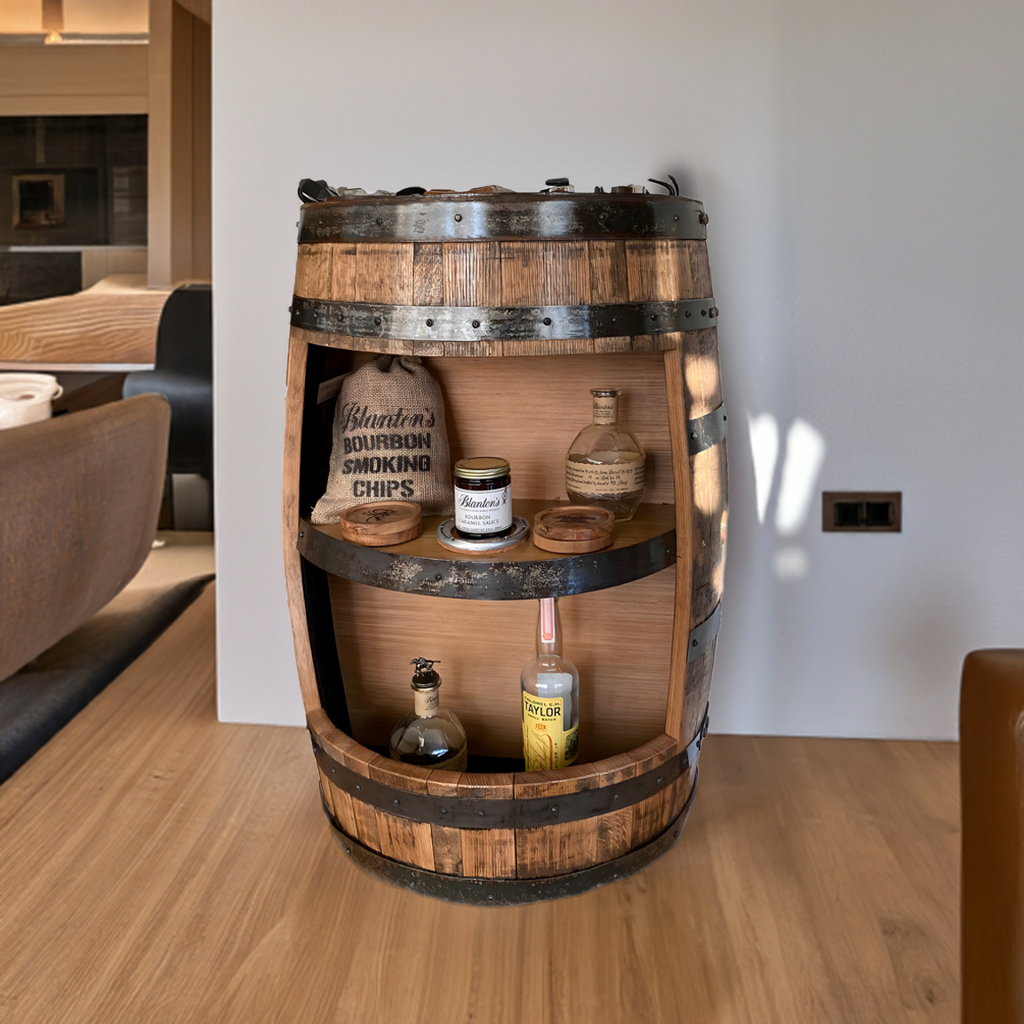 The Half Barrel Open Cabinet with Shelves is a handmade solid wood mini bar, perfect for rustic decor, holding bottles, tins, and bourbon smoking chips against a white wall.
