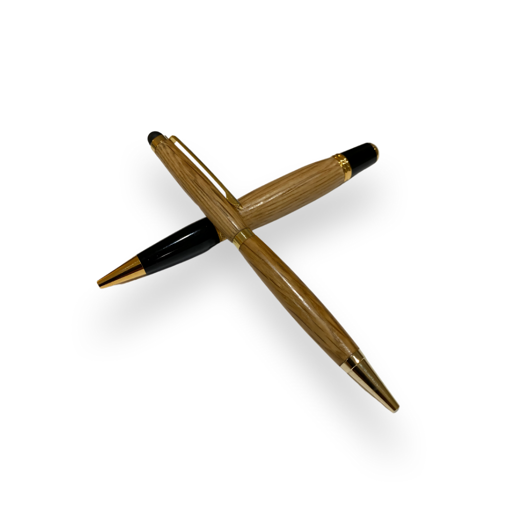 Two Barrel Pens, handcrafted from reclaimed oak whiskey barrels with gold accents, are crossed over each other on a white background.