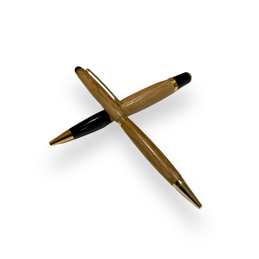 Two Barrel Pens, handcrafted from reclaimed oak whiskey barrels with gold accents, are crossed over each other on a white background.