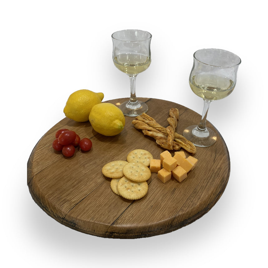 The Lazy Susan Round Swivel Wooden Tray, hand made from solid wood barrel head, beautifully displays crackers, cheese cubes, cherry tomatoes, lemons, bread twists, and wine—finished to be food-safe for stylish serving.