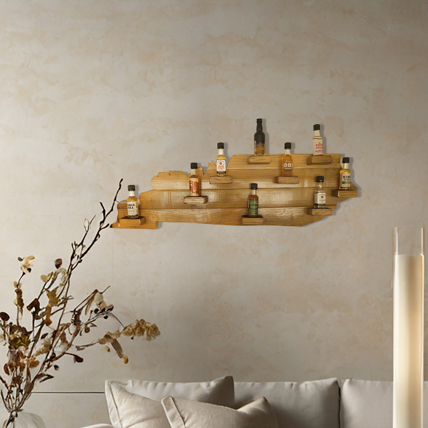 The Kentucky Wood Map Shelf, made from reclaimed whiskey barrels, displays small bottles above a beige couch with branch accents—an eye-catching piece that adds unique charm to your home decor.