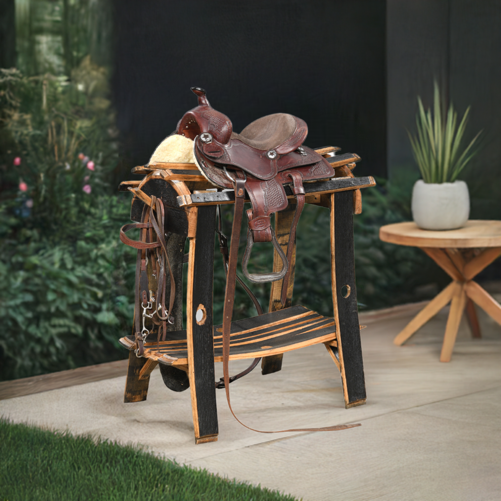 A Saddle Stand, crafted from sturdy wood, is placed outdoors beside a small round table, supporting a brown leather horse saddle and highlighting artisan craftsmanship with rustic elegance.