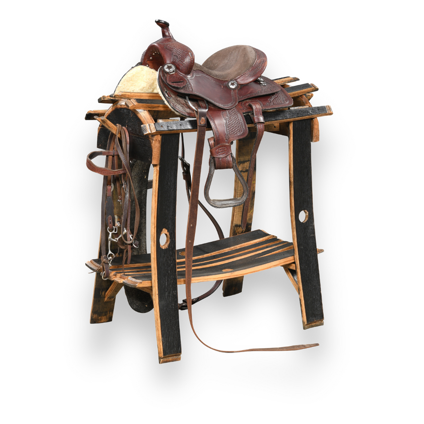 A Saddle Stand in natural wood supports a brown leather horse saddle with artisan craftsmanship, set against a white background.