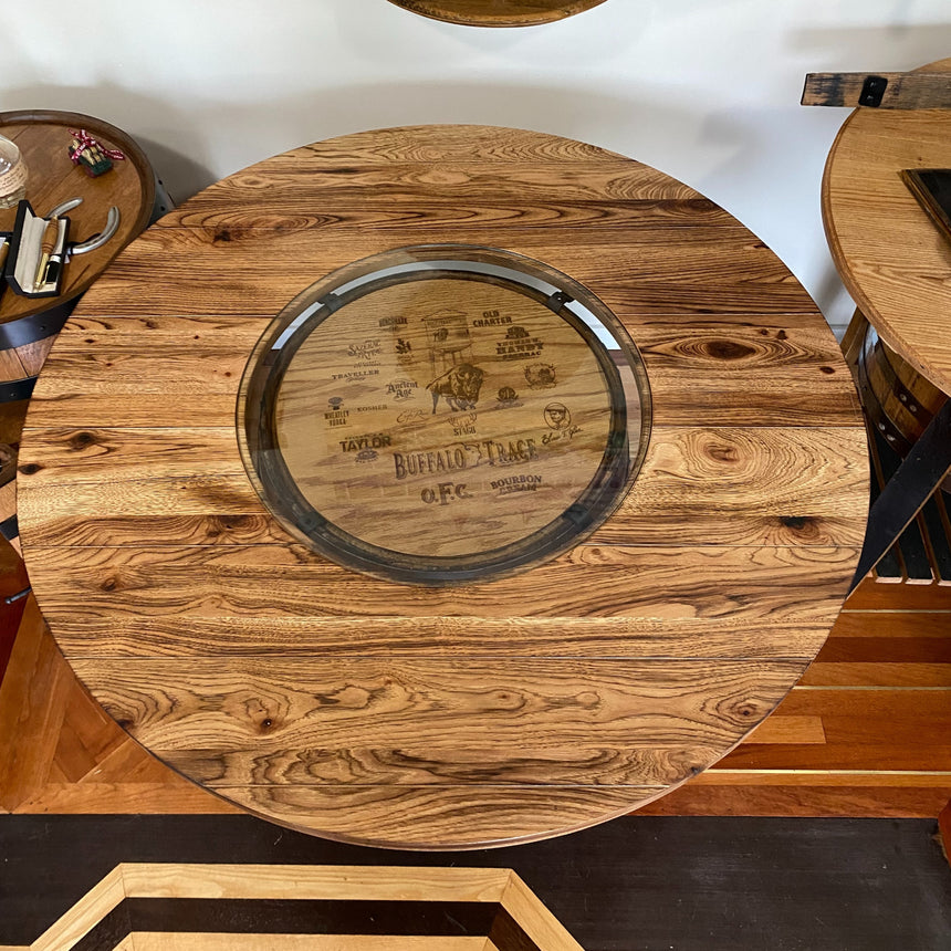 The Whiskey Barrel Burnt Hickory Tabletop With Glass Inlay features a handcrafted wooden design and glass center, showcasing a decorative Buffalo Trace distillery barrel top for unique rustic charm.