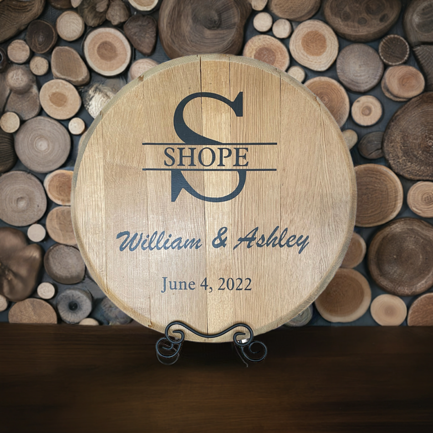The Whiskey Barrel Head Wedding Special is a wooden sign engraved with “Shope, William & Ashley, June 4, 2022”—a unique personalized keepsake crafted from authentic bourbon barrel heads.