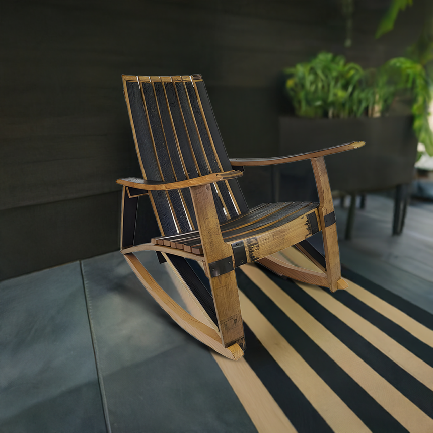 The Whiskey Barrel Stave Adirondack Chair Rocker, featuring black slats and ergonomic design, rests on a black and beige striped rug with plants in the background.