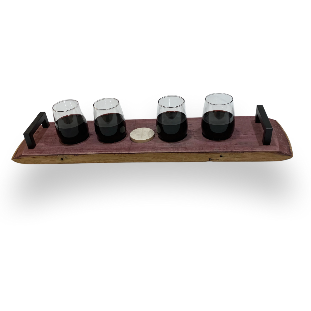 Four glasses of dark liquid sit on a Wine Barrel Serving Board made from reclaimed barrels, featuring sturdy black metal handles and a center-set coin.
