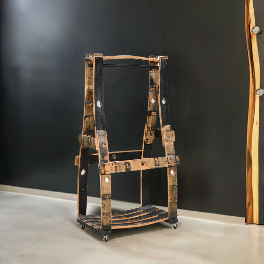 The Barrel Garment Rack, crafted from an eco-friendly reclaimed whiskey barrel and set on wheels, is displayed in a modern gallery space.
