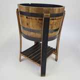 The ½ Barrel Cooler No Top - T009, featuring black metal bands that exude rustic charm, is mounted on a wooden stand with a slatted lower shelf, making it perfect for outdoor entertaining.