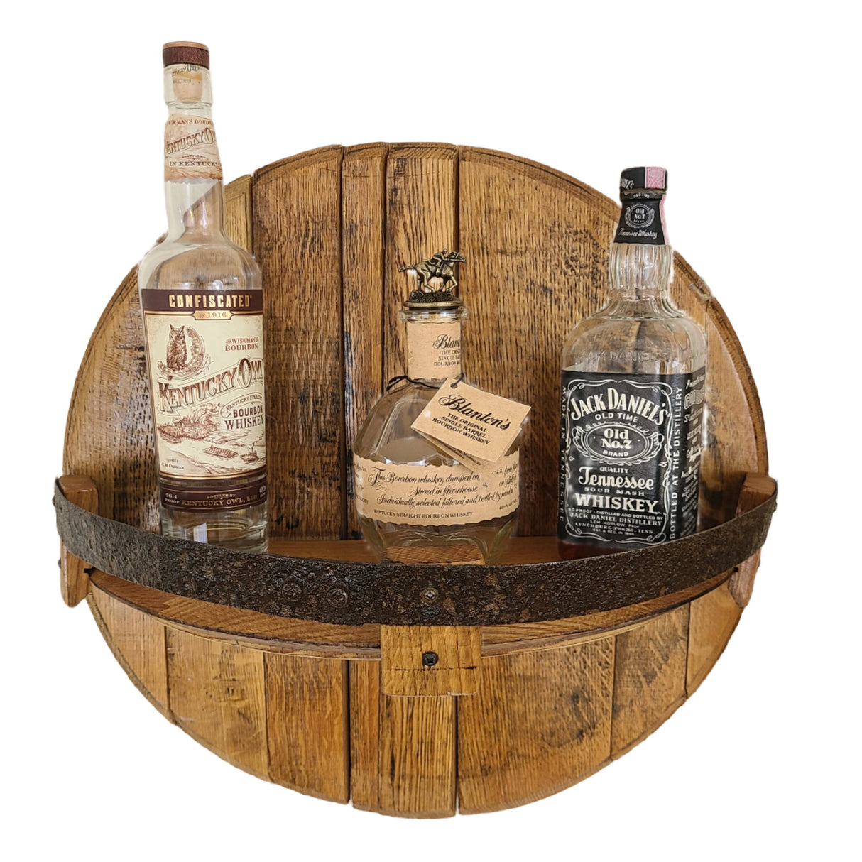 A Barrel Head Shelf with Half Band - A001, priced at $150.00, exudes rustic sophistication and features three distinguished whiskey bottles: Kentucky Owl, Blanton's, and Jack Daniel's. This unique piece transforms whiskey barrels into a stylish showcase for your finest spirits.