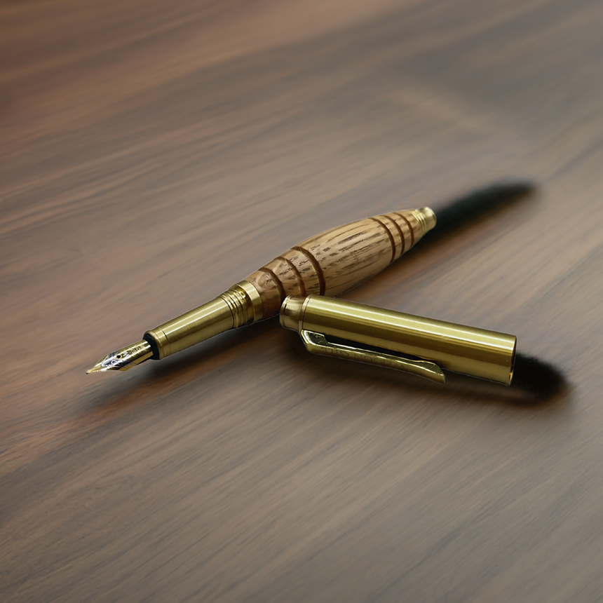 The Bourbon Barrel Fountain Pen, handcrafted with a wooden barrel from reclaimed Kentucky bourbon barrels and a gold cap, rests on a polished wooden surface.