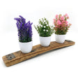 Three small potted plants with purple, white, and pink flowers are displayed on a Bud Vase Stand, crafted from reclaimed whiskey barrels.