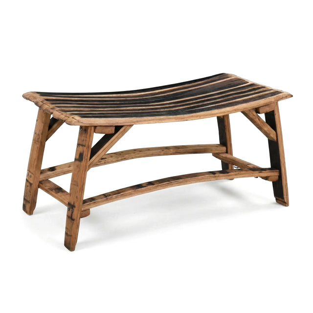 The Barrel Stave Bench features a curved slatted seat and natural wood finish, crafted in a rustic style inspired by classic whiskey barrel furniture.