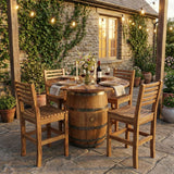 A rustic patio features a Barrel Dinner Table And Dinner Chairs set, illuminated by string lights and complemented by a wine set for dinner.