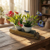 Two small potted flower plants, one red and one blue, sit on a wooden tray beside the Double Bud Vase Whiskey Staves—a perfect rustic touch for your sunlit tabletop decor.