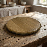A Lazy Susan Round Swivel Wooden Tray, handmade from solid wood barrel heads, sits on a rustic wooden table in a sunlit kitchen.