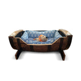 A plush toy lion rests in a blue cushioned Dog Bed Wooden, handmade from a solid wood barrel frame—perfect for small and medium-sized dogs.