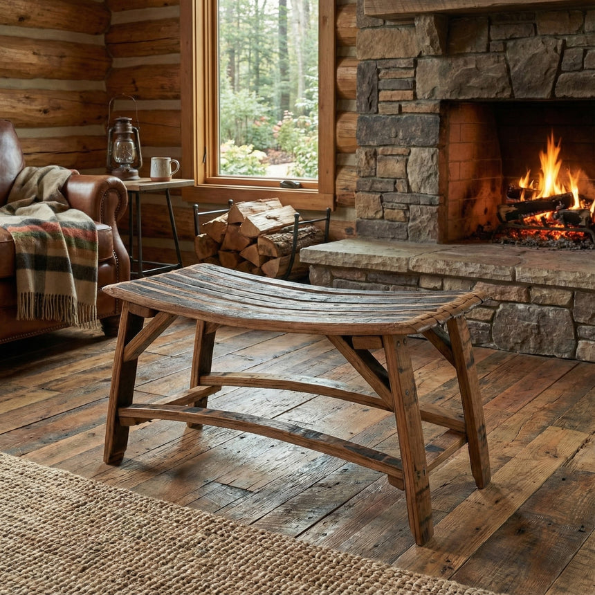A rustic log cabin room features a stone fireplace, wooden furniture, and a cozy fire. A Barrel Stave Bench adds unique charm, blending bourbon barrel craftsmanship into the warm, inviting space.