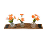 Three glass vases with orange flowers sit on the Bud Vase Stand, made from reclaimed whiskey barrels with metal accents and a curved wood tray, all displayed against a white background.