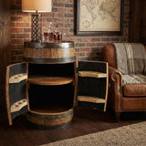 A Full Barrel Cabinet with shelves and glassware holders, hand made from wood barrels, serves as a full bar beside a leather chair and lamp—perfect for a rustic home bar atmosphere.