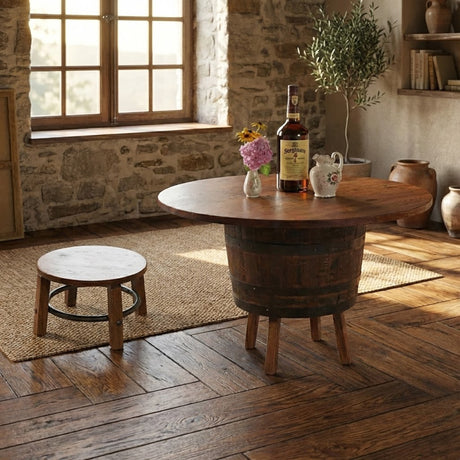 A rustic room featuring a Barrel Table with Legs, whiskey bottle, flowers, small stool, and sunlight streaming in through the window creates timeless charm.