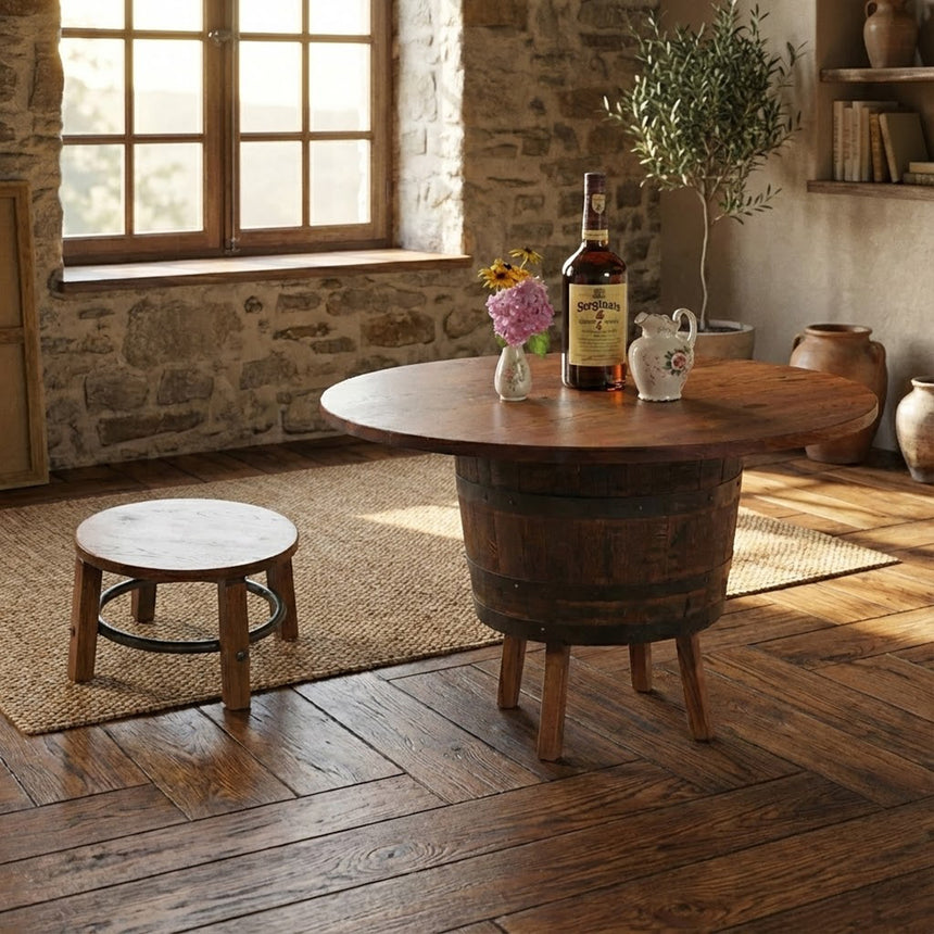 A rustic room featuring a Barrel Table with Legs, whiskey bottle, flowers, small stool, and sunlight streaming in through the window creates timeless charm.