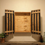 The handcrafted Dart Board Cabinet, made from solid wood barrel staves and fitting a standard tournament spec dart board, sits above a shelf with decor—an ideal game room accent.