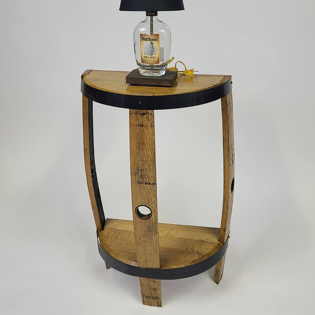 The Lamp Side Table - T005, priced at $185.00, combines the rustic charm of a versatile side table made from a wooden barrel with the unique touch of a lamp featuring a bourbon bottle as its base, perfect for enhancing your home decor.