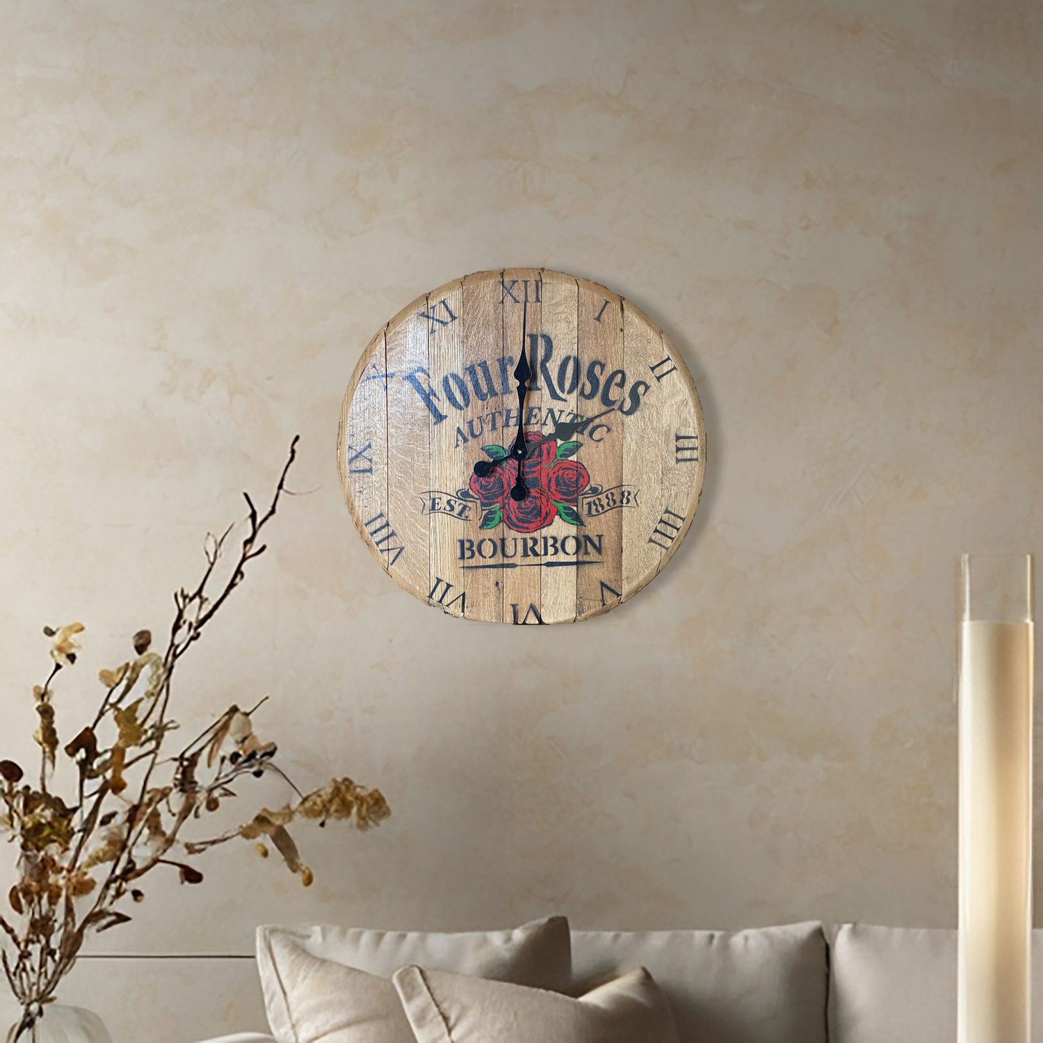 A Four Roses Bourbon Inspired Wooden Wall Clock, hand made with solid wood, hangs above a beige sofa and is complemented by nearby plants.