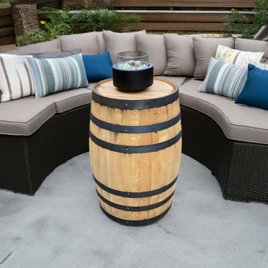 A Pub Table Glass Fire Top serves as a centerpiece in front of a curved outdoor sofa with cushions.