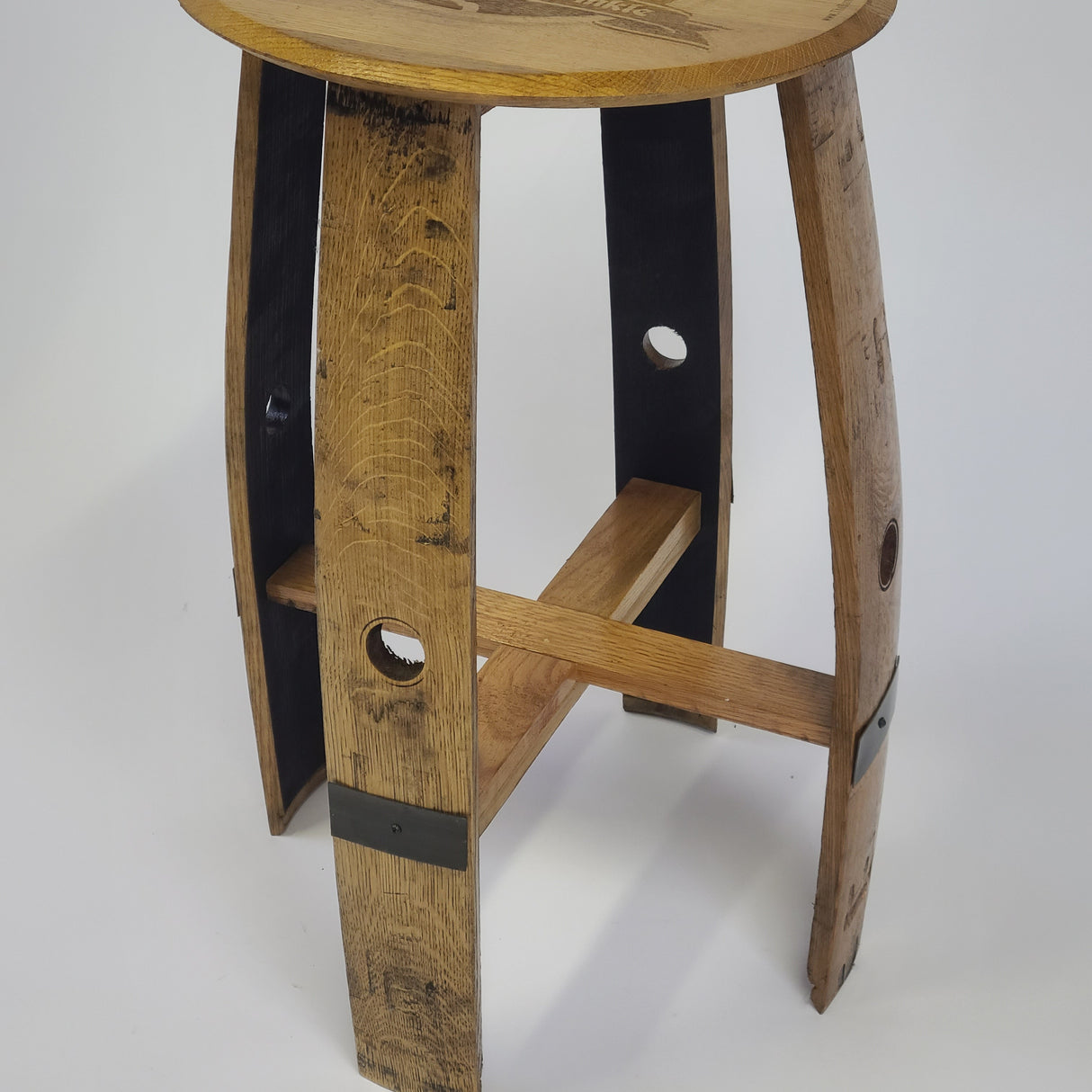 A rustic Pub Table - T005 featuring a round wooden top, wooden legs with metal accents, and cross supports, perfect for an elegant and versatile dining and social experience. Priced between $200.00 to $400.00.