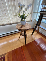 A Stave whiskey barrel plant stand, featuring a potted orchid, is positioned near a window with vertical blinds in a sunlit room.