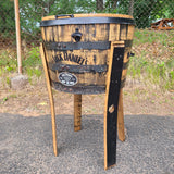 A Whiskey Barrel Cooler with Lid, priced at $395.00 (T008), repurposed into a large planter exudes rustic charm as it stands on a paved surface near a fence.