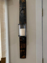 A Whiskey Barrel Stave Candle Sconce, priced at $75.00, mounted on a beige wall near a corner.