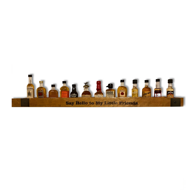 The Whiskey Barrel Stave Shelf for Nippers, featuring "Say Hello to My Little Friends" carved on the front, elegantly displays mini liquor bottles with rustic charm.