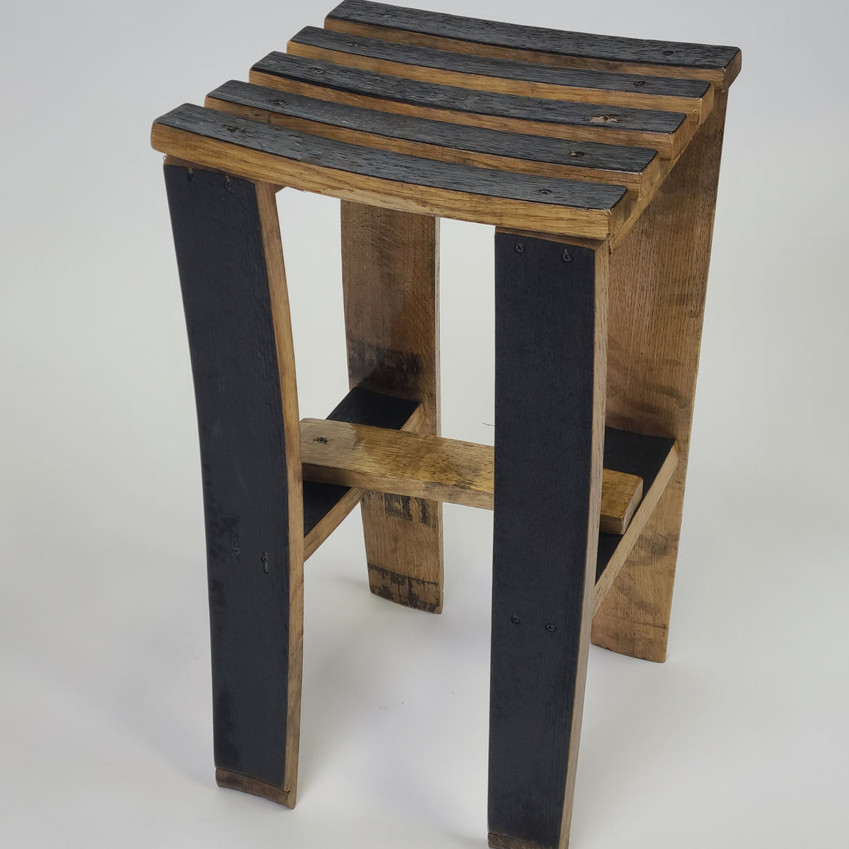 The Whiskey Barrel Stave Stool - S001, priced at $125.00, features a slatted seat and an alternating light and dark wood finish, exuding rustic elegance.