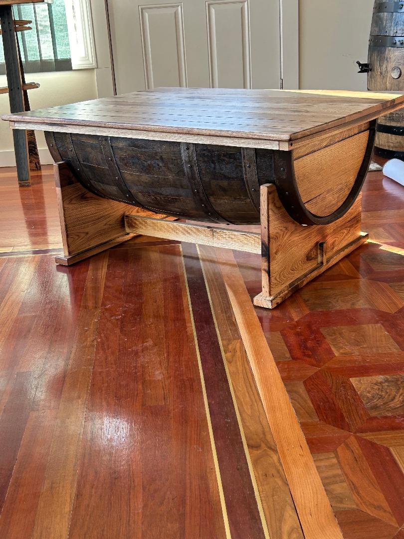 Introducing the Whiskey Half Barrel Coffee Table with Lift Top for $935.00 - featuring a burnt hickory top that combines rustic charm and functionality. This square table showcases a distinctive lift top and proudly displays its base made from reclaimed wooden barrels, making it a perfect accent on any decorative wooden floor.