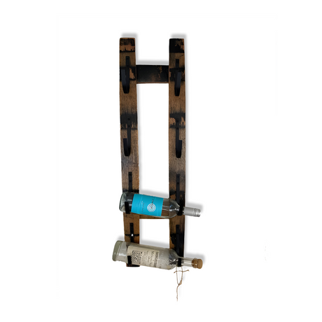 The Whiskey Stave Wine Holder exudes rustic elegance, crafted from barrel staves to hold two wine bottles, one brown and one teal.