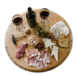 A charcuterie board featuring wine, cheese, cured meats, bread, olives, and nuts elegantly arranged on a Lazy Susan Round Swivel Wooden Tray with hand-made solid wood barrel head construction and a food-safe finish.