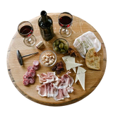 A charcuterie board featuring wine, cheese, cured meats, bread, olives, and nuts elegantly arranged on a Lazy Susan Round Swivel Wooden Tray with hand-made solid wood barrel head construction and a food-safe finish.