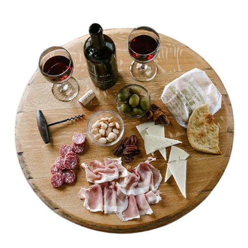 A charcuterie board featuring wine, cheese, cured meats, bread, olives, and nuts elegantly arranged on a Lazy Susan Round Swivel Wooden Tray with hand-made solid wood barrel head construction and a food-safe finish.