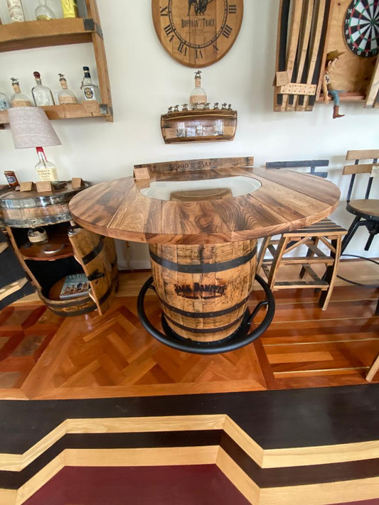 A home bar area showcasing a Jack Daniels Pub Table with a 48" burnt hickory and glass insert top, wooden stools, bottles on shelves, and parquet flooring. Price: $1375.00.