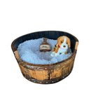 A plush pillow bed holds a stuffed dog and mini whiskey barrel, nestled in a charming, hand-made round frame dog bed crafted from premium reclaimed oak barrels.